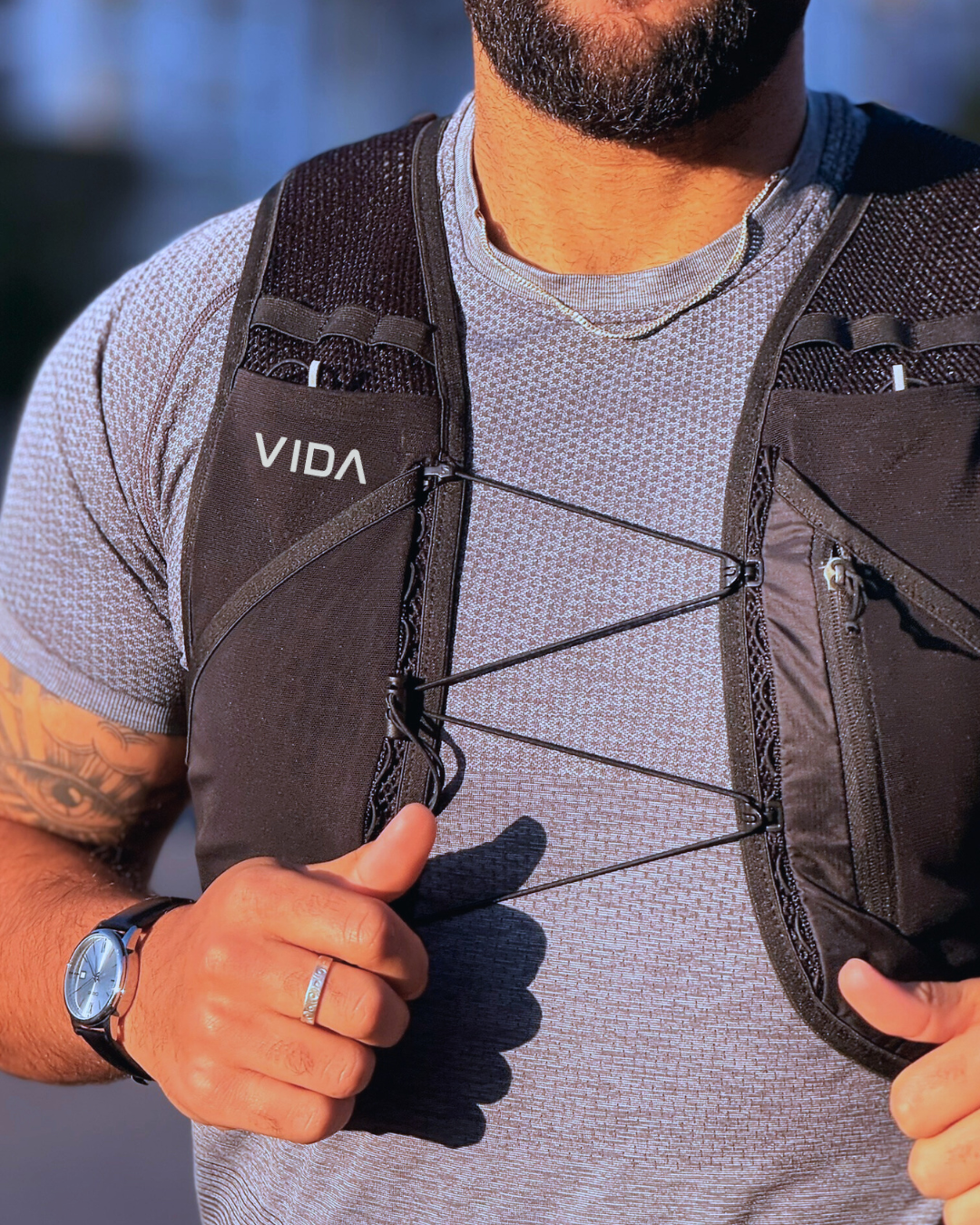 Person wearing a black VIDA backpack with a blurred background