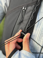 Person adjusting a black string on a black running vest with a blurred background